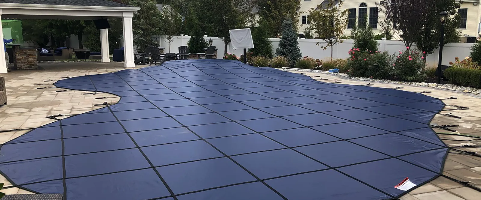 Mesh winter safety cover installed over a backyard pool